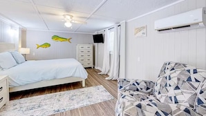 A bedroom with a bed, a dresser, an air conditioner, and a patterned sofa. - Pet Friendly & Private 3BR Raised Home, Blocks to the Beach! (North Myrtle Beach)