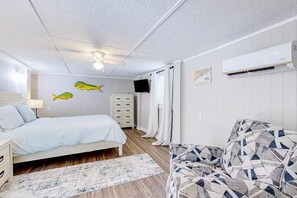 Una camera da letto con un letto, una cassettiera, un condizionatore d'aria e un divano a motivi.