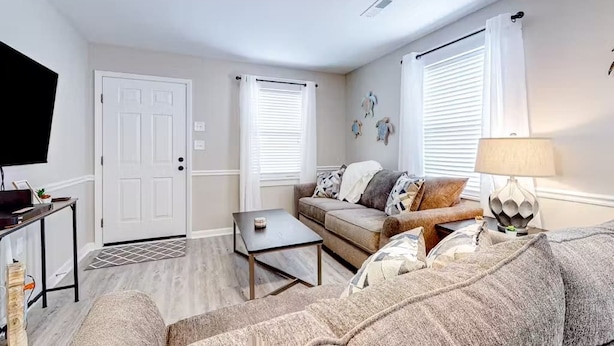 A living room with a sofa, a coffee table, a TV, and a lamp. - Pet Friendly & Private 3BR Raised Home, Blocks to the Beach! (North Myrtle Beach)
