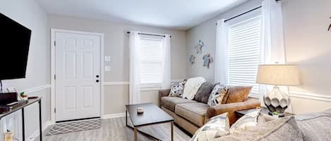 A living room with a sofa, a coffee table, a TV, and a lamp.