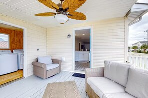 A covered porch with a ceiling fan, wicker furniture, and a view of the backyard.