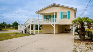 A two-story house with a covered porch and a staircase leading to the upper level. - Pet Friendly & Private 3BR Raised Home, Blocks to the Beach! (North Myrtle Beach)