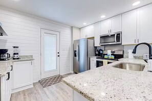 A modern kitchen with white cabinetry, stainless steel appliances, and a granite countertop.