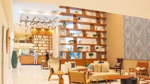 A modern interior with a central wooden bookshelf, a seating area with sofas and chairs, and a patterned wall. - Beach and luxury with ideal location (Mazatlán)