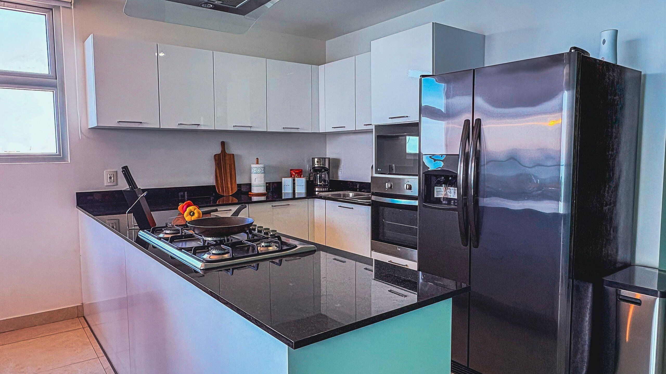 A modern kitchen with white cabinets, a black refrigerator, and stainless steel appliances.