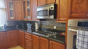 Una cocina con armarios de madera, estufa a gas, microondas y horno.