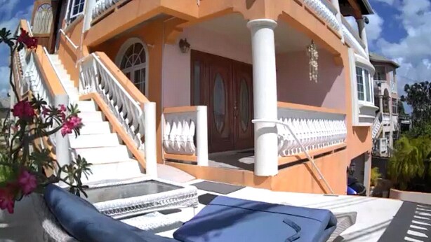 Un edificio de dos pisos con un balcón, una escalera y un ventanal grande.