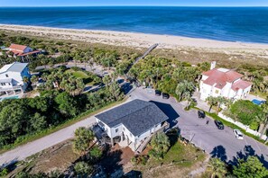Situated on a sandy beach, this coastal property offers a scenic view of the surrounding greenery and palm trees.