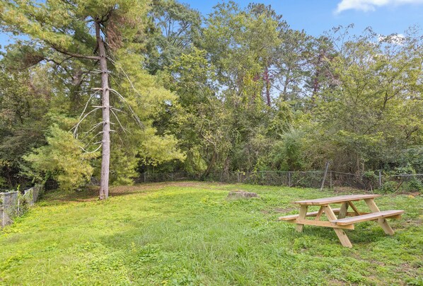 A picnic table in a grassy area with trees and a fence in the background. - Trendy at Hoyt Two Homes (Chattanooga)