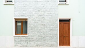 Un bâtiment doté d’une façade en pierre, d’une porte en bois et d’une fenêtre ornée d’un rideau.