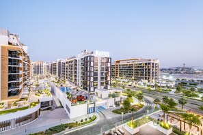 A modern residential complex with multiple high-rise buildings, a swimming pool, and well-maintained landscaping. - Relaxing 1BR Apartment with Built-in Wardrobe & Community View in Azizi Riviera 4, Al Merkadh (Dubai)