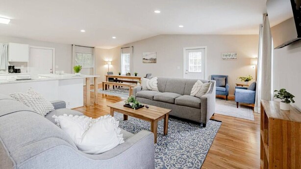 A modern living room with a grey sofa, a coffee table, and a dining area with a table and chairs. - Columbia Duet Unit B (West Columbia)