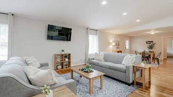 Un soggiorno moderno con un divano grigio, un tavolino da caffè e una TV a parete.