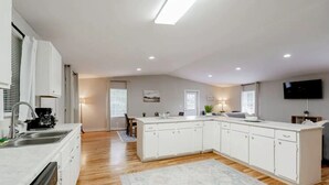 A modern kitchen with white cabinetry, a built-in dishwasher, and a large island. - Columbia Duet Unit B (West Columbia)