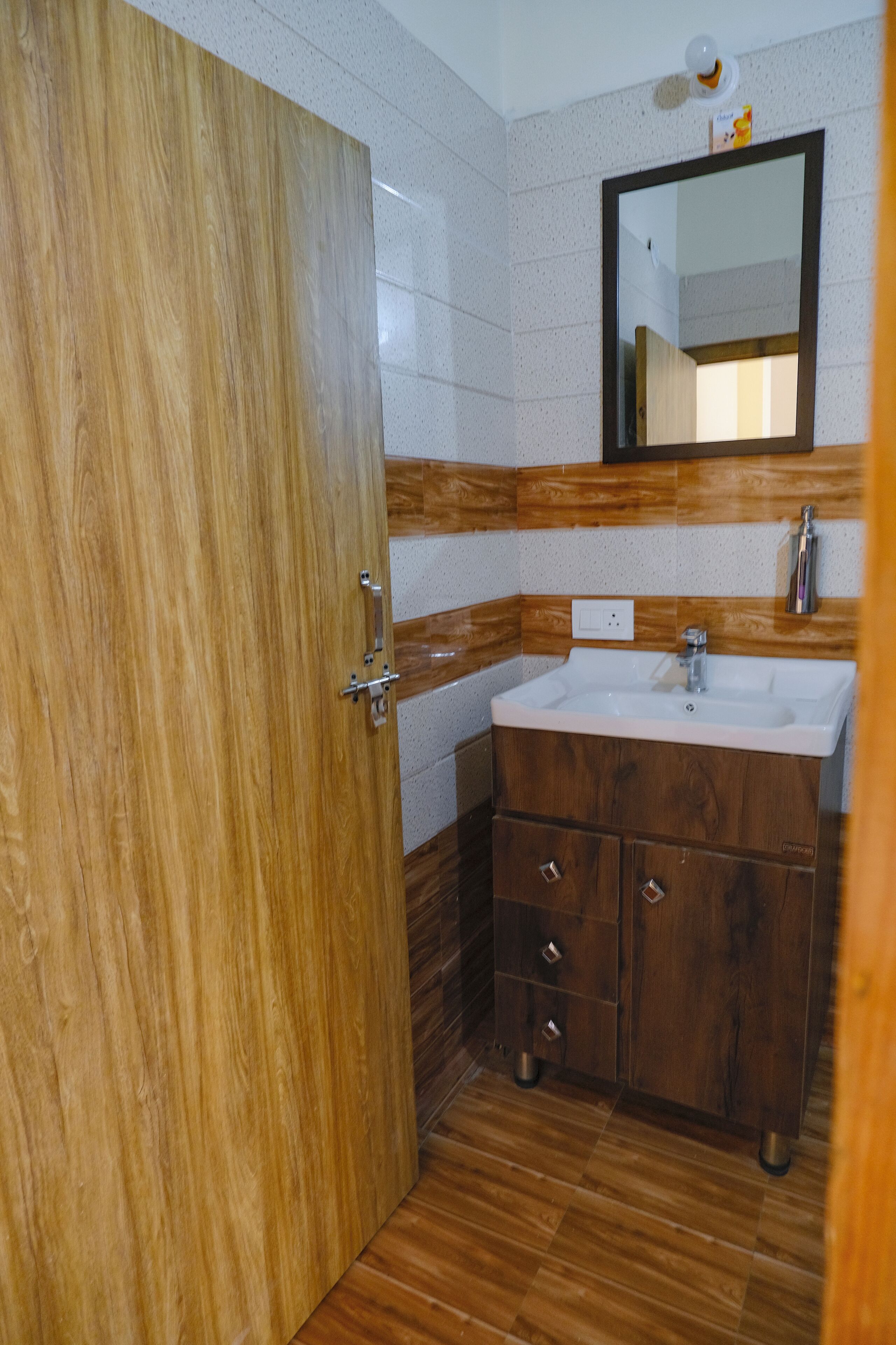 A bathroom with a wooden door, a sink, and a mirror.