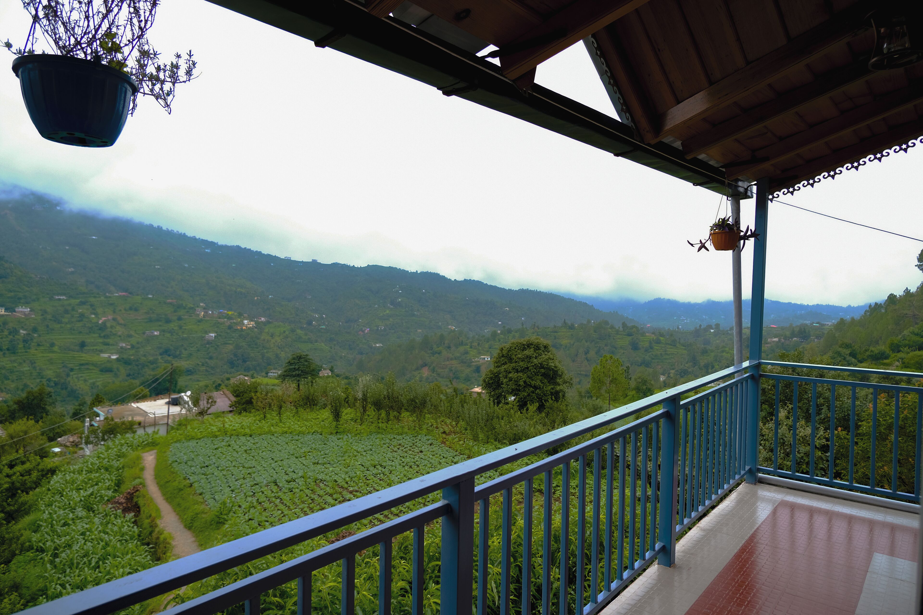 A balcony with a view of a lush valley and distant mountains.