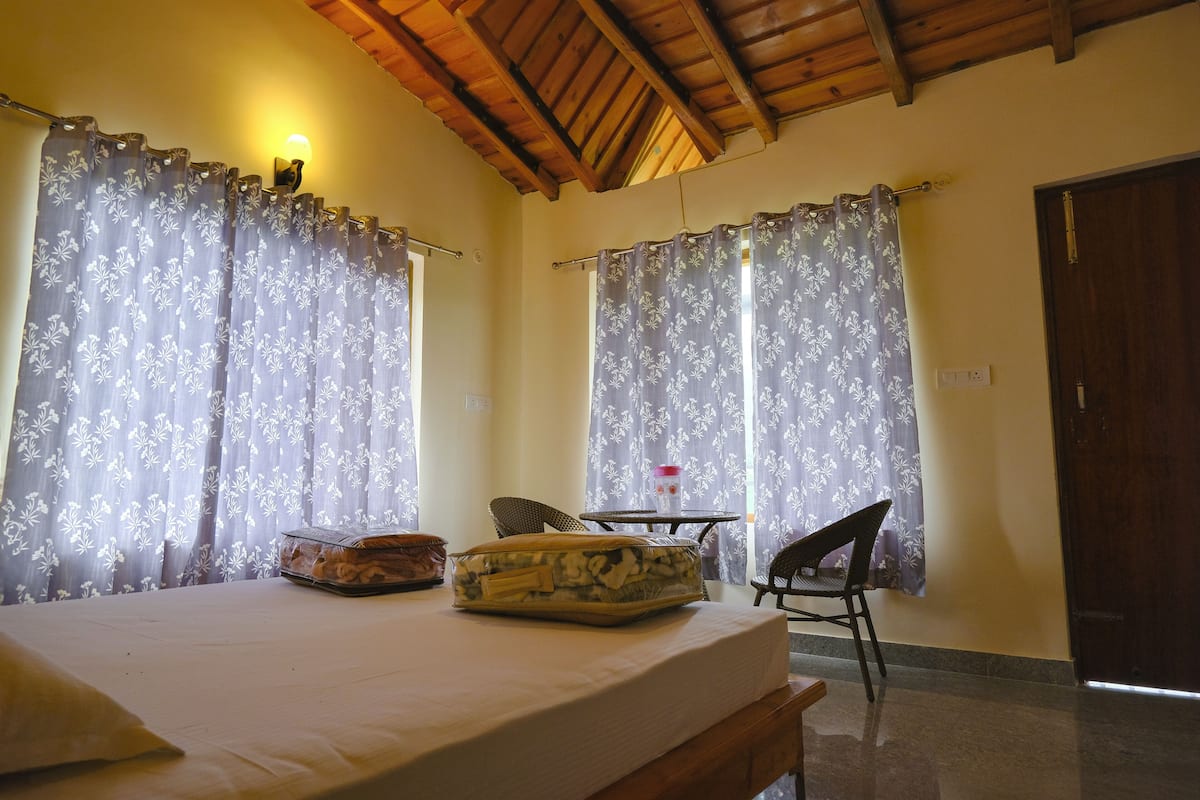 Um quarto com cama, uma cadeira, uma mesa e cortinas.