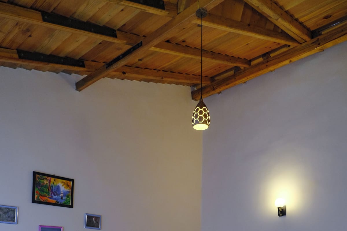 Quarto com cama de madeira, mesa de vidro e uma cadeira.