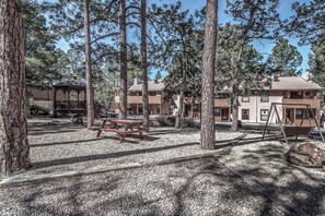 A forested area with picnic tables, a gazebo, and cabins. - Pinon Park C11 | Cozy, Fireplace, Great Location (Ruidoso)
