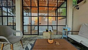 A room with a wooden table, a grey chair, a blue side table, and a white sofa. - Alban, Longo Mai - Cabaña Aqua - Via Namay Alto (Alban)
