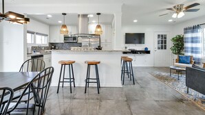Une cuisine moderne dotée d’un îlot central, de tabourets de bar et d’un coin repas avec une table et des chaises.