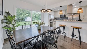 Une cuisine moderne dotée d’un îlot central, de tabourets de bar et d’une table à manger avec des chaises.