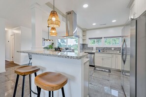 Una cocina moderna con una isla central, electrodomésticos de acero inoxidable y vistas al exterior.