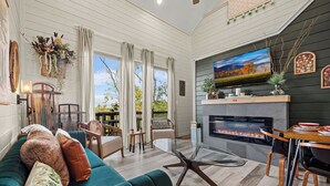 A modern living room with a glass coffee table, a fireplace, a TV, and a cozy seating area.