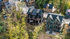 A cluster of cabins with multiple stories and balconies, surrounded by dense forest.