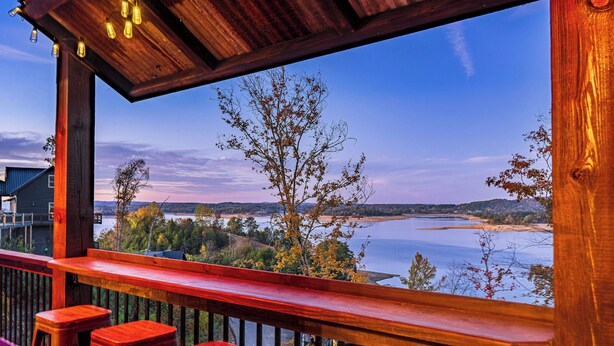 A wooden deck with a view of a lake and distant hills.
