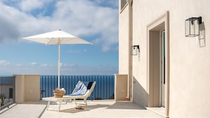 Un balcon avec un parasol blanc, une chaise longue et un panier en osier.