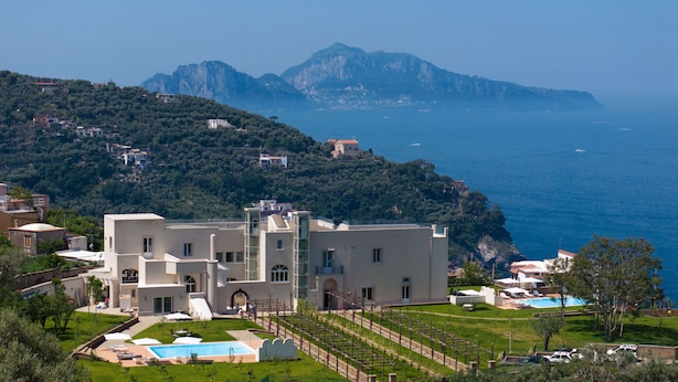 Une villa située sur la côte, dotée d’une piscine, d’un jardin et offrant une vue sur la mer et les montagnes.