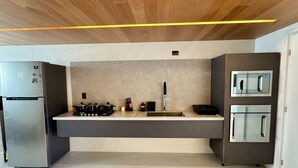 Eine moderne Küche mit Holzbalkendecke, Edelstahlgeräten und schlichtem Design.
