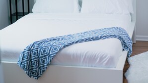 Una cama bien hecha con ropa blanca y un edredón estampado en azul.
