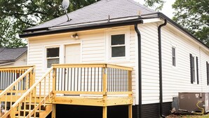 Una casa de dos pisos con un deck de madera y una antena parabólica.
