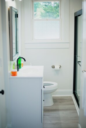 Een badkamer met een witte wastafel, een groene zeepdispenser en een toilet.