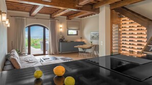 Una cocina moderna con encimera negra, un comedor con mesa y sillas, y vistas al exterior a través de un ventanal grande.