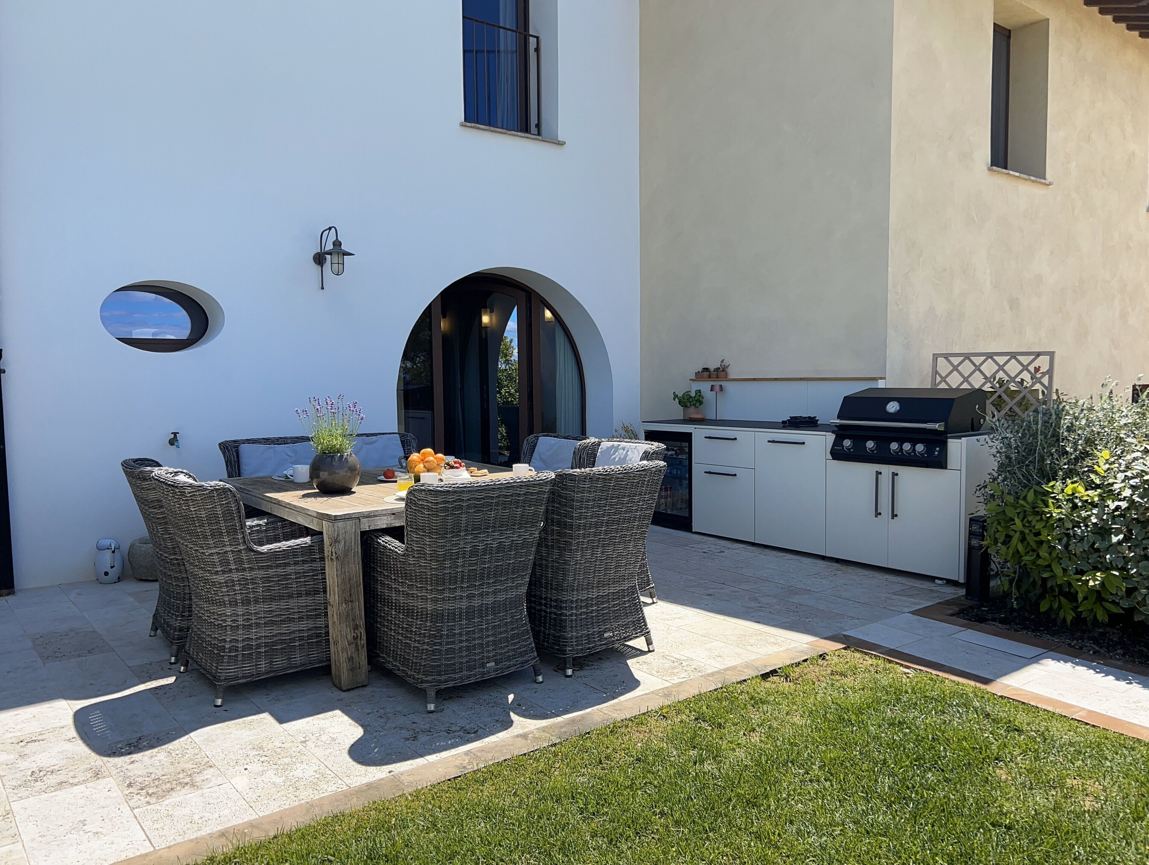 An outdoor patio with a dining table and chairs, a grill, and a small kitchen area.