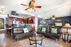 Una sala de estar moderna con sofás de cuero, una mesa de centro de vidrio y una cocina al fondo.