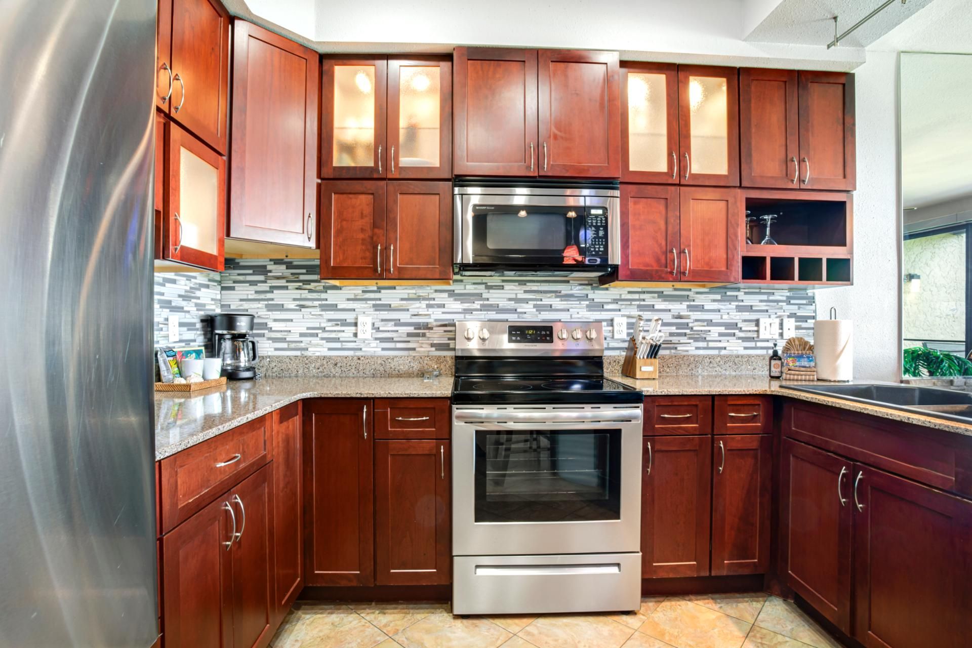 A kitchen with wooden cabinets, a stainless steel refrigerator, a microwave, and an oven.