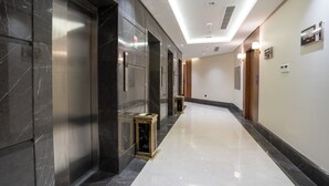 Ein moderner Hotelkorridor mit Marmorwänden, einem polierten Boden und einer Decke mit eingelassener Beleuchtung.