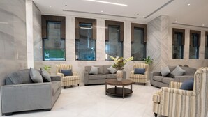 Ein modernes Wohnzimmer mit einem grauen Sofa, gestreiften Sesseln und einem runden Couchtisch.