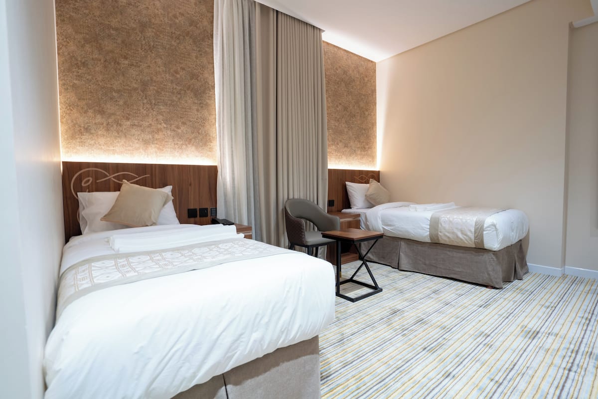 Una habitación de hotel con dos camas, un escritorio y una silla.
