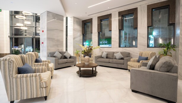 Eine moderne Lobby mit gestreiften Sofas, einem zentralen Couchtisch und großen Fenstern.