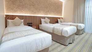 Ein Hotelzimmer mit zwei Betten, einer großen Wandleuchte und einem Streifen Teppich.