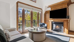 A modern living room with a fireplace, a flat-screen TV, and a cozy seating area with a sofa and a round coffee table.