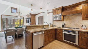 A modern kitchen with wooden cabinets, stainless steel appliances, and a large island with a dishwasher.