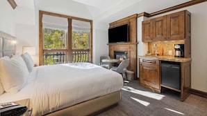 A bedroom with a large bed, a TV, a fireplace, and a small kitchen area. - The Aspen Mountain Residences 32A - Studio Residence (Aspen)