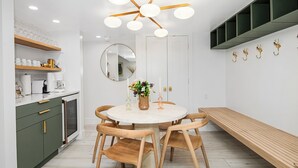 A modern kitchen with a round dining table, wooden chairs, and a built-in bench.