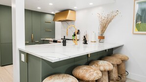A modern kitchen with a large island, bar stools, and a decorative vase.